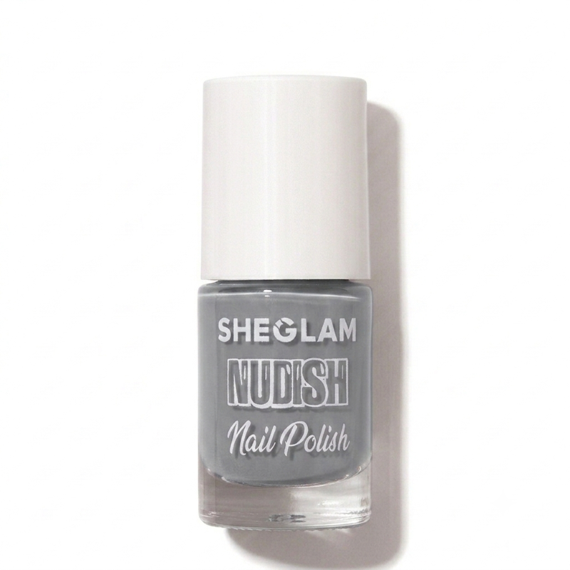 A bottle of SHEGLAM Nudish Nail Polish in a light gray shade, featuring a white cap and clear glass bottle, set against a plain white background with a soft shadow.